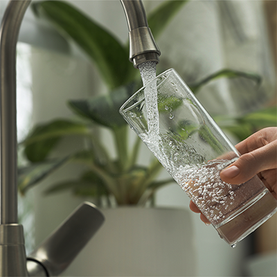 Filling a glass of tap water for testing